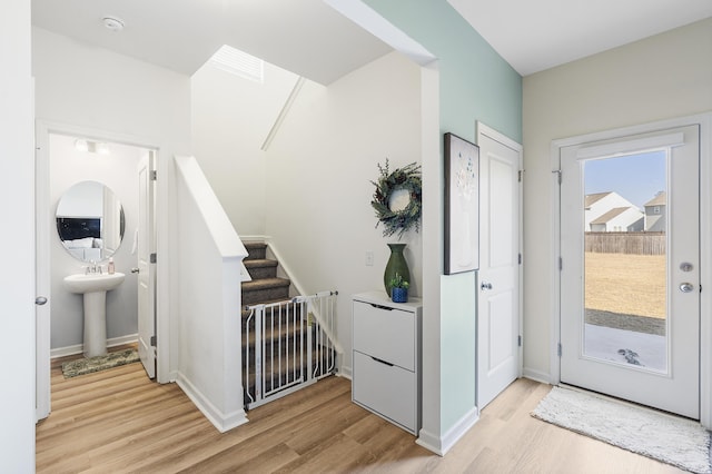 entryway with stairs, light wood-style flooring, and baseboards