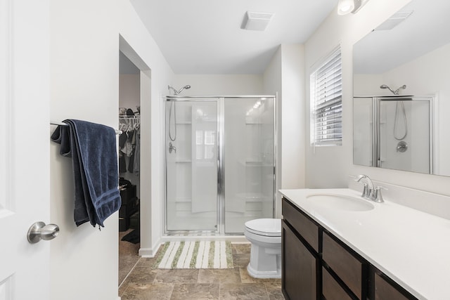 full bathroom featuring toilet, a stall shower, a spacious closet, and vanity