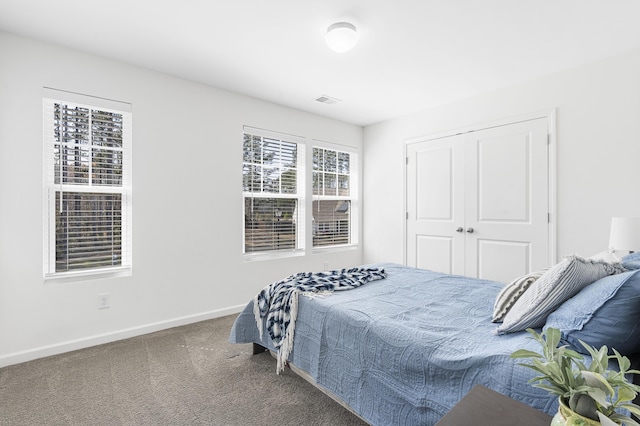 bedroom featuring a closet, carpet flooring, visible vents, and baseboards