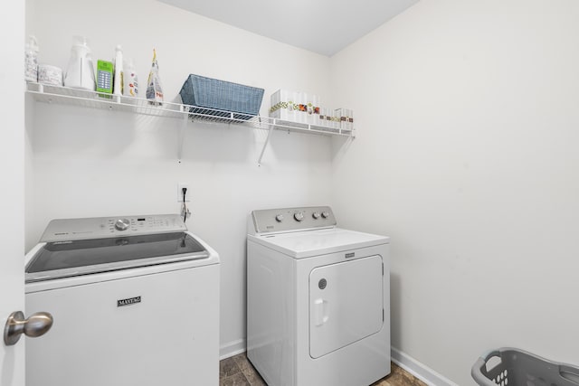 clothes washing area with laundry area, washing machine and clothes dryer, and baseboards