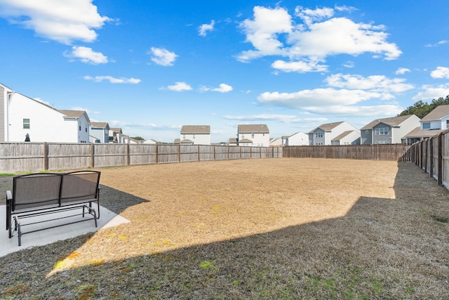 view of yard featuring a residential view, a patio area, and a fenced backyard