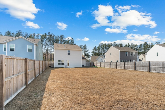 rear view of house with a residential view, a fenced backyard, and a lawn