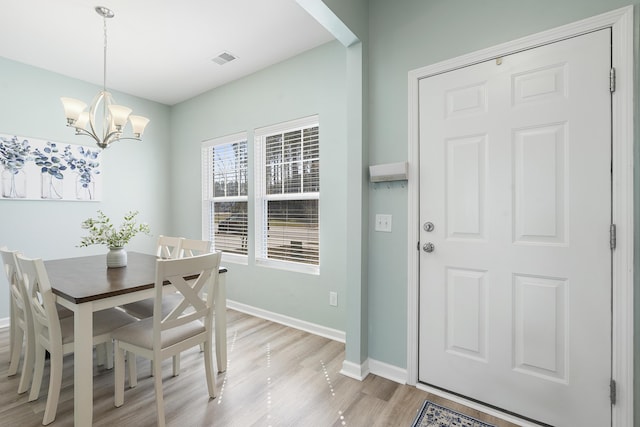 dining area with light wood-style floors, baseboards, visible vents, and a chandelier