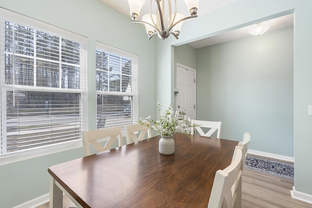 dining room featuring light wood-type flooring, an inviting chandelier, and baseboards