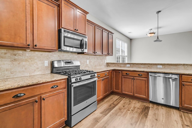 kitchen featuring light stone counters, decorative backsplash, light wood-style floors, appliances with stainless steel finishes, and brown cabinets