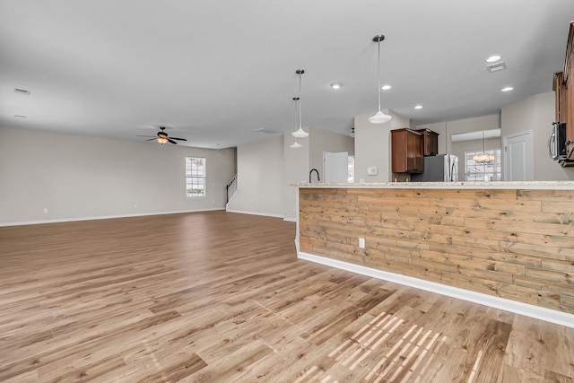 kitchen with baseboards, light wood-style floors, hanging light fixtures, stainless steel appliances, and a ceiling fan