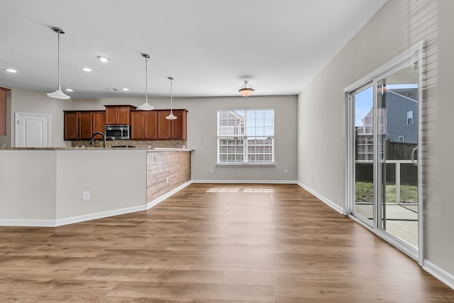 kitchen with pendant lighting, stainless steel microwave, wood finished floors, recessed lighting, and baseboards