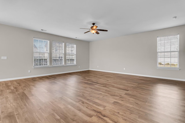 unfurnished room featuring visible vents, baseboards, wood finished floors, and a ceiling fan