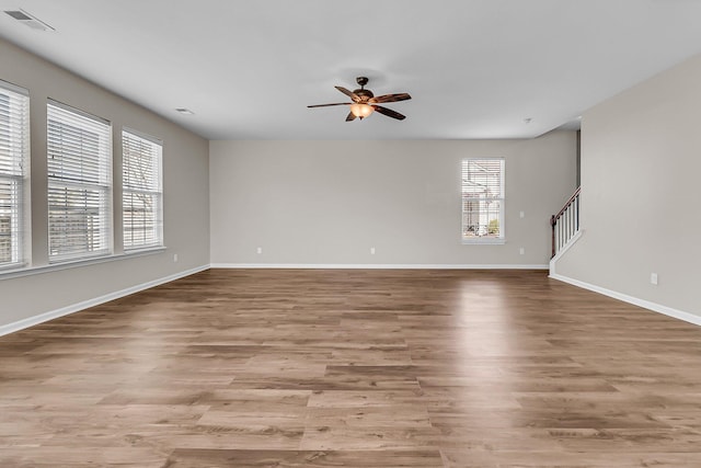 unfurnished living room with visible vents, stairway, light wood-type flooring, and ceiling fan