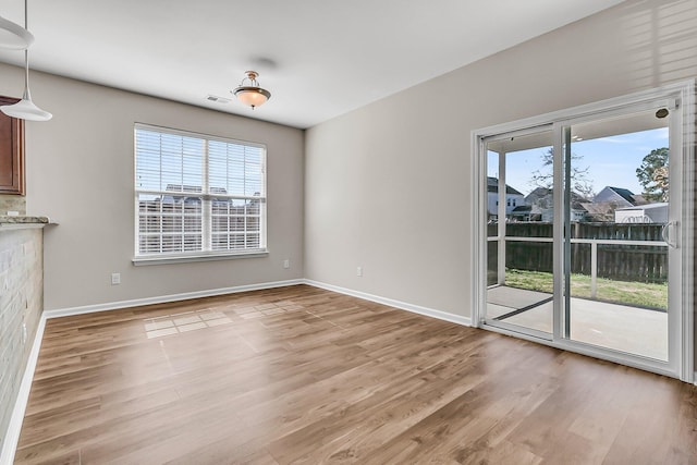 unfurnished dining area with light wood-type flooring, plenty of natural light, and baseboards