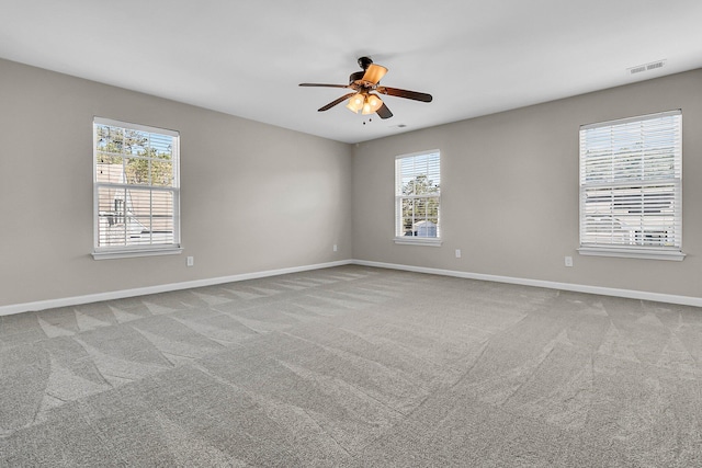 unfurnished room with carpet flooring, baseboards, a wealth of natural light, and ceiling fan