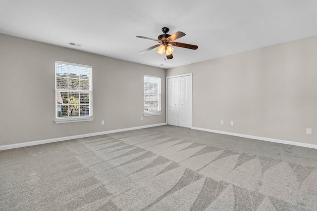 empty room with baseboards, carpet floors, visible vents, and a ceiling fan