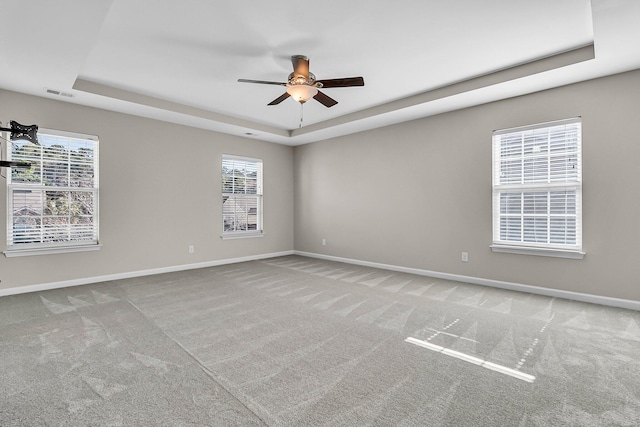 unfurnished room with visible vents, a tray ceiling, carpet floors, baseboards, and ceiling fan