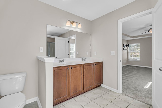 bathroom featuring toilet, a ceiling fan, a sink, double vanity, and baseboards