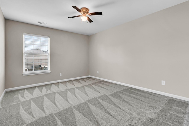 spare room with carpet flooring, a ceiling fan, visible vents, and baseboards