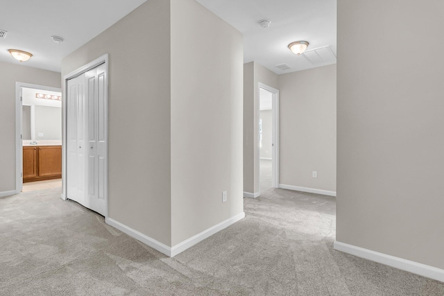 hallway featuring baseboards and light carpet