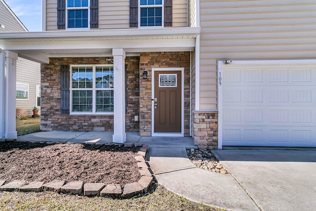 doorway to property with a garage, stone siding, and covered porch