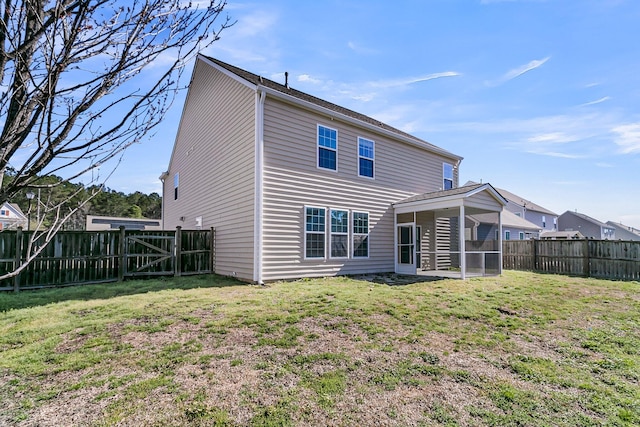 rear view of house featuring a gate, a lawn, a fenced backyard, and a sunroom