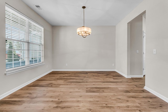 unfurnished room featuring wood finished floors, visible vents, and baseboards