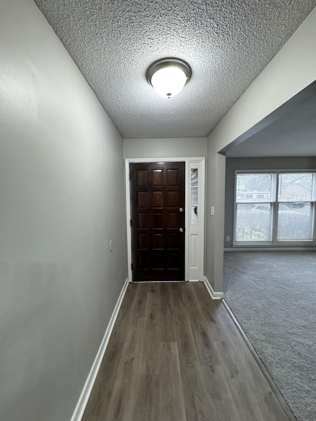 entrance foyer with carpet, a textured ceiling, baseboards, and wood finished floors