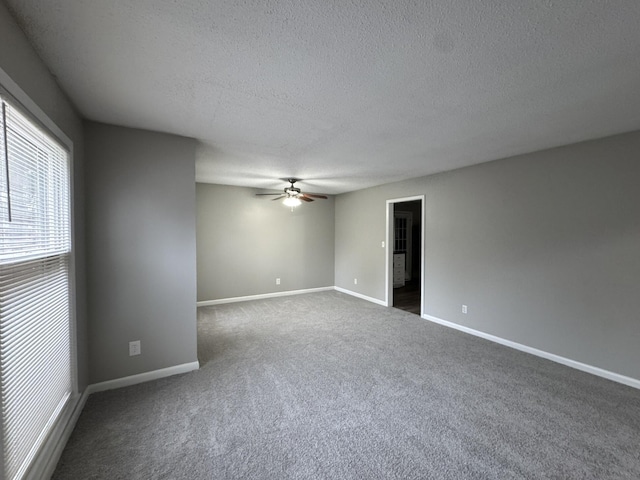 carpeted spare room featuring a textured ceiling, a ceiling fan, and baseboards