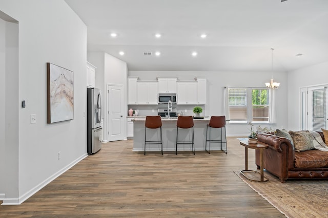 209 Country Gate Ln, Summerville, SC 29485 - kitchen with appliances with stainless steel finishes, wood finished floors, a breakfast bar area, a kitchen island with sink, and white cabinetry