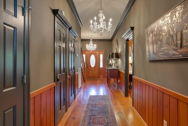 doorway featuring a notable chandelier, light hardwood / wood-style floors, and ornamental molding