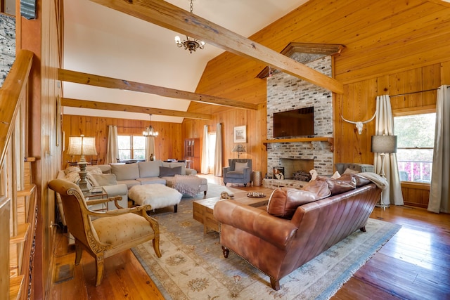 living room featuring a chandelier, light wood-type flooring, high vaulted ceiling, and a brick fireplace