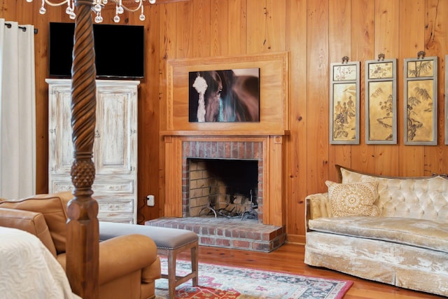 living room with a brick fireplace, wooden walls, and hardwood / wood-style flooring