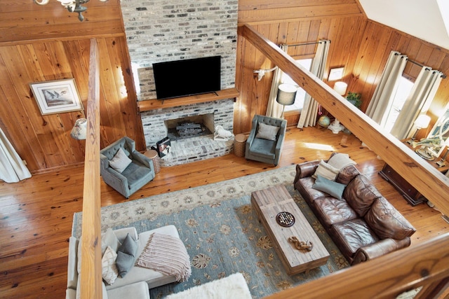 living room featuring hardwood / wood-style flooring, wood walls, a fireplace, and vaulted ceiling