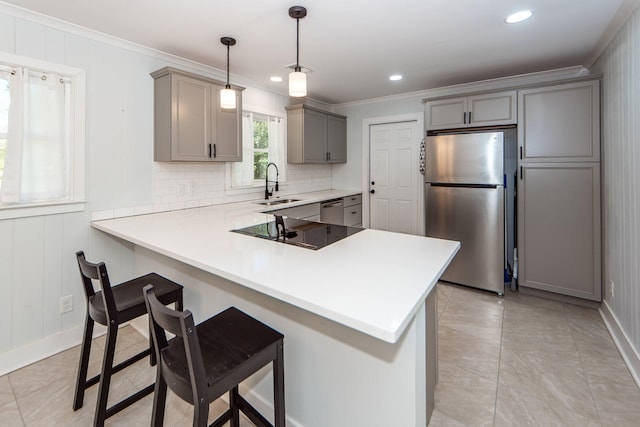 kitchen with sink, hanging light fixtures, kitchen peninsula, a kitchen bar, and appliances with stainless steel finishes