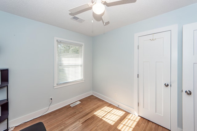 spare room with light hardwood / wood-style flooring, ceiling fan, and a textured ceiling