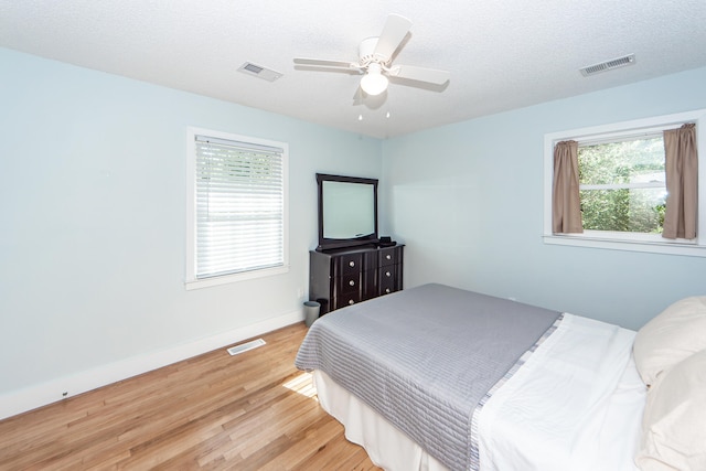 bedroom with ceiling fan, hardwood / wood-style flooring, and a textured ceiling