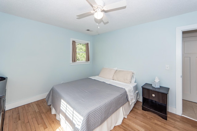 bedroom with ceiling fan, light hardwood / wood-style floors, and a textured ceiling