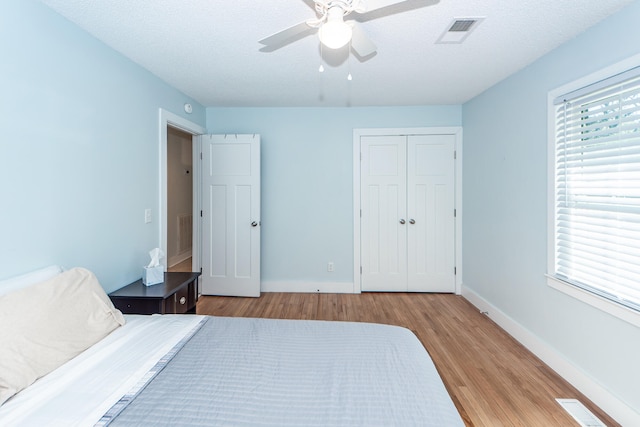 bedroom with ceiling fan, a closet, a textured ceiling, and light wood-type flooring