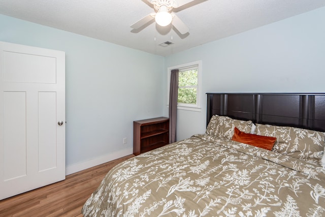 bedroom featuring hardwood / wood-style floors, a textured ceiling, and ceiling fan