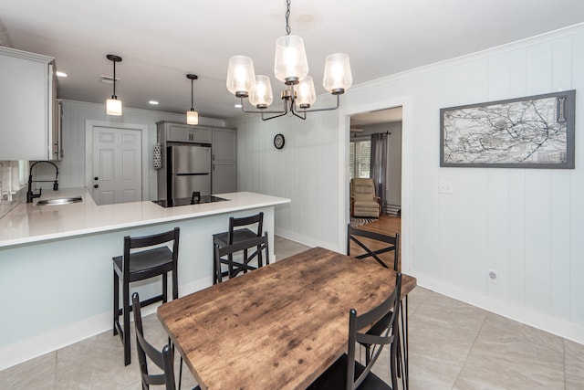 dining area featuring wooden walls, ornamental molding, sink, and a notable chandelier