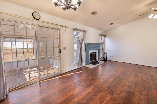 unfurnished living room with hardwood / wood-style flooring, ceiling fan with notable chandelier, vaulted ceiling, and a brick fireplace