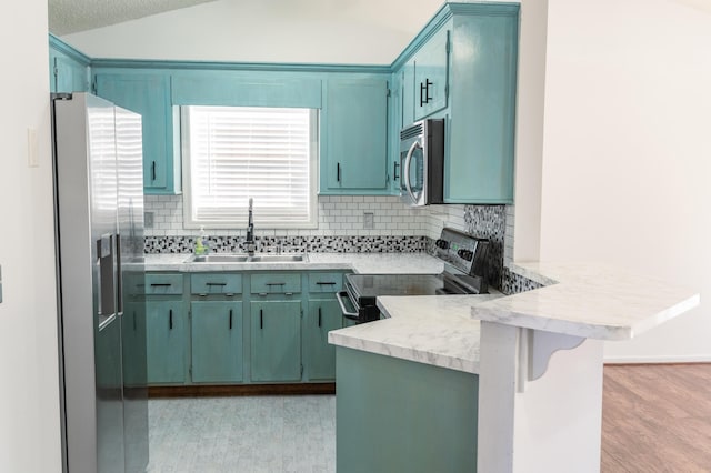 kitchen with kitchen peninsula, appliances with stainless steel finishes, sink, lofted ceiling, and a breakfast bar area