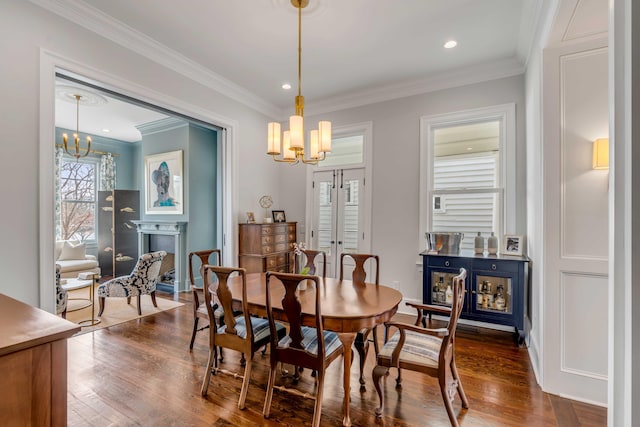 dining space with ornamental molding, a fireplace, a chandelier, and dark wood finished floors