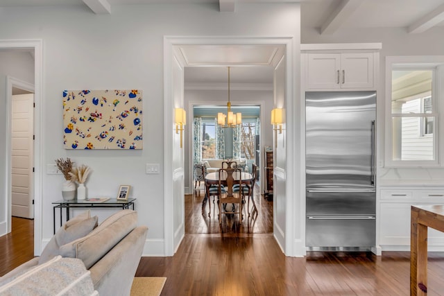 interior space featuring dark wood finished floors, stainless steel built in fridge, a chandelier, and white cabinets