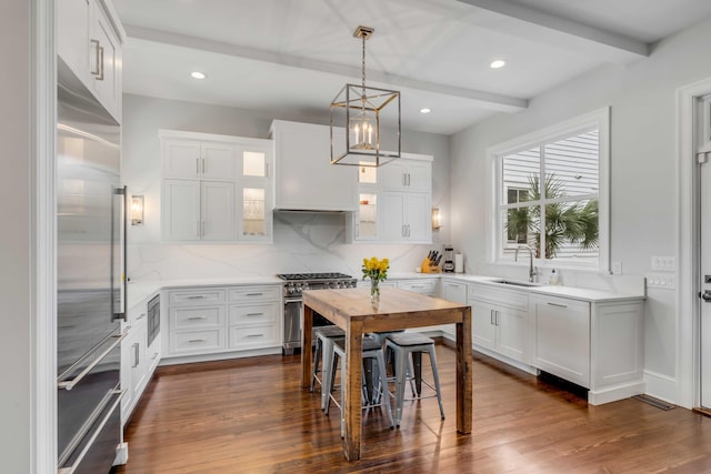 kitchen featuring built in appliances, a sink, backsplash, beam ceiling, and dark wood-style floors