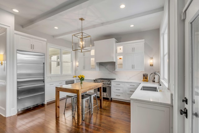 kitchen featuring a sink, high end appliances, dark wood-style floors, and beam ceiling