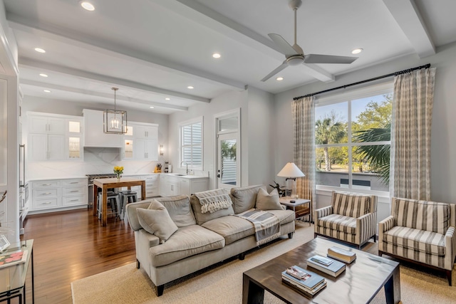 living area featuring a ceiling fan, dark wood-style floors, plenty of natural light, and beam ceiling