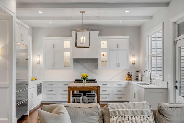 kitchen featuring built in appliances, beamed ceiling, light countertops, and white cabinets