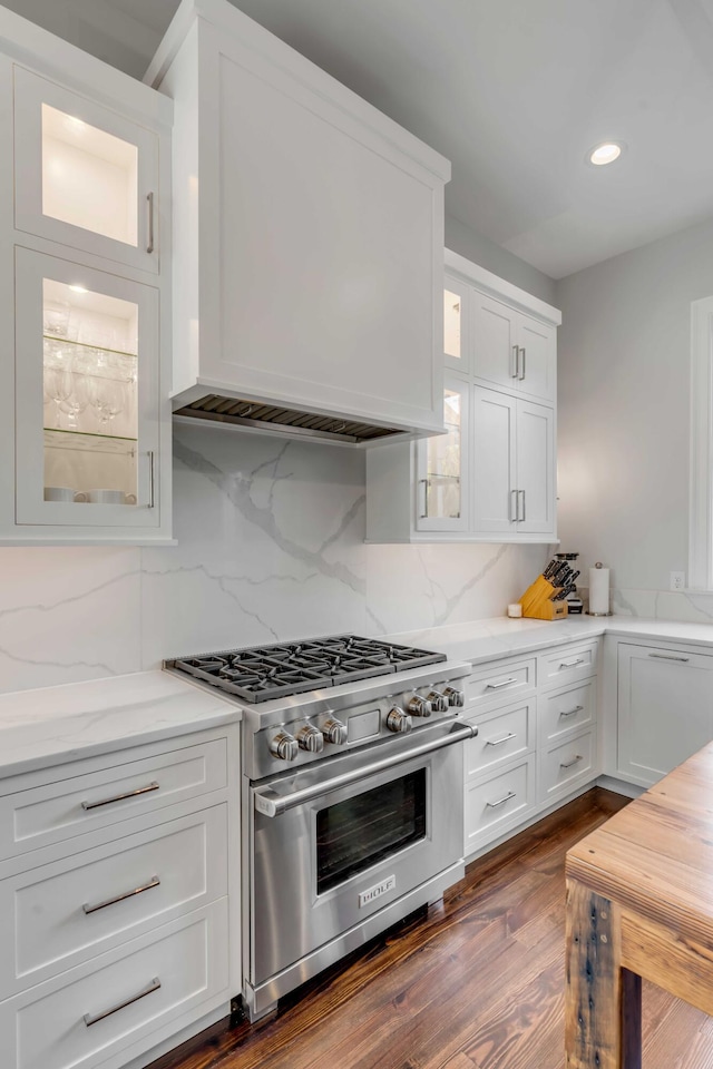 kitchen featuring high end stainless steel range, white cabinets, custom range hood, and glass insert cabinets