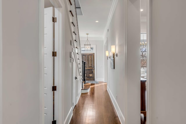 hall featuring recessed lighting, dark wood-style flooring, crown molding, a notable chandelier, and baseboards