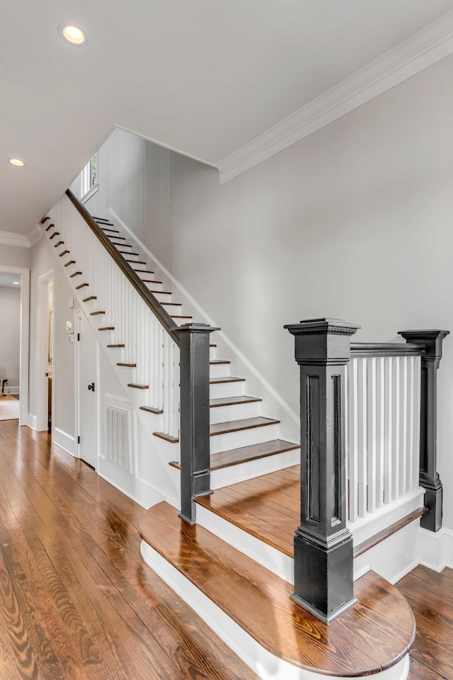 staircase featuring recessed lighting, baseboards, ornamental molding, visible vents, and hardwood / wood-style flooring
