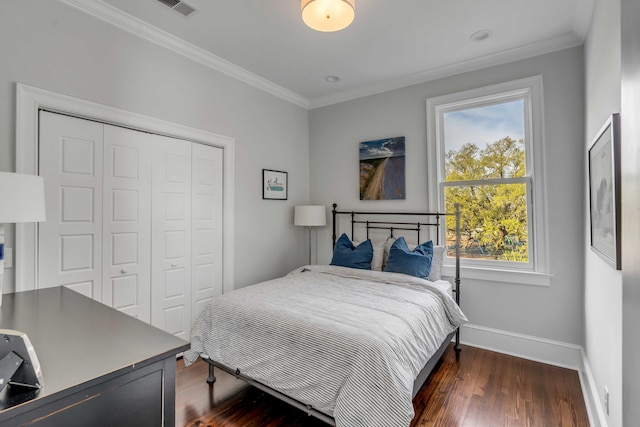 bedroom with a closet, ornamental molding, dark wood-type flooring, visible vents, and baseboards