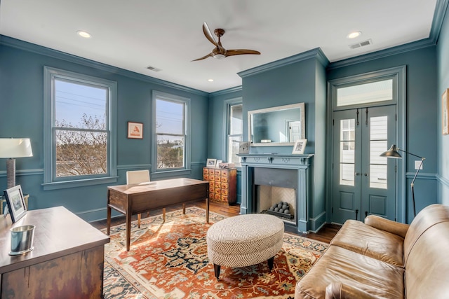 office space featuring a ceiling fan, ornamental molding, visible vents, wood finished floors, and a fireplace